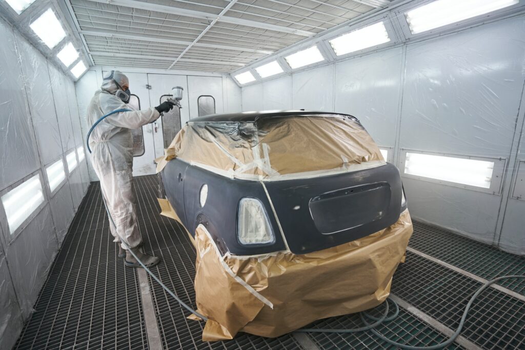 Process of painting car with spray gun in workshop